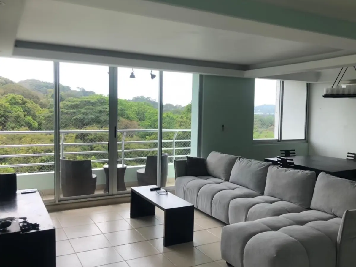 Living room of a three-bedroom apartment at Clayton Park in Clayton, with a grey sectional sofa, a black coffee table and sliding doors to a balcony.