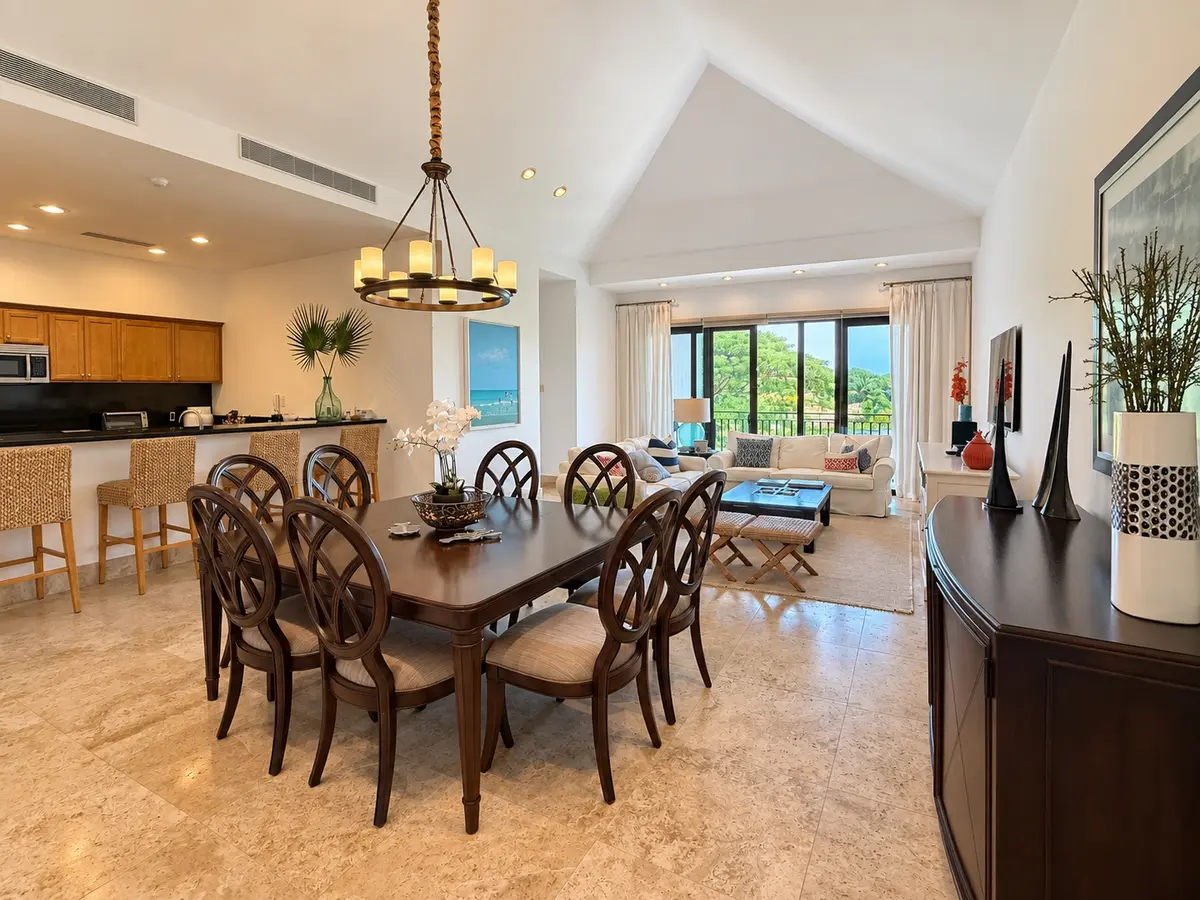 Comedor del apartamento 322 en Paseo de las Casas bajo techo abovedado, con mesa de madera oscura para ocho, candelabro de hierro y la barra de la cocina.